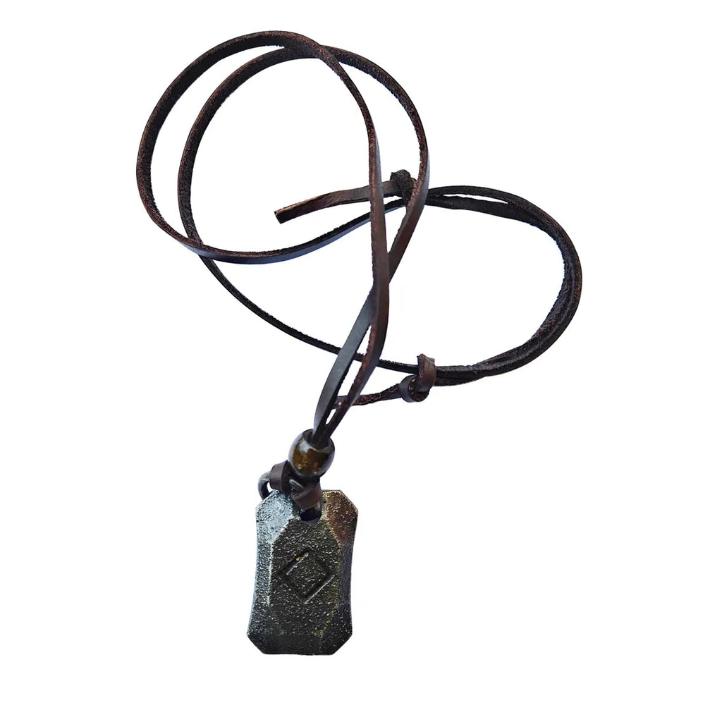 The Viking Rune Pendant Ingwaz is a black stone pendant with an engraved design, hanging from a dark brown leather cord that's loosely coiled against a white background.