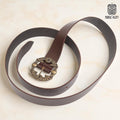 The Norse Alley The Drakkar Belt is a long brown Viking leather belt with an ornate Norse-patterned metal buckle, displayed on a light surface with the Norse Alley logo in the top right corner.