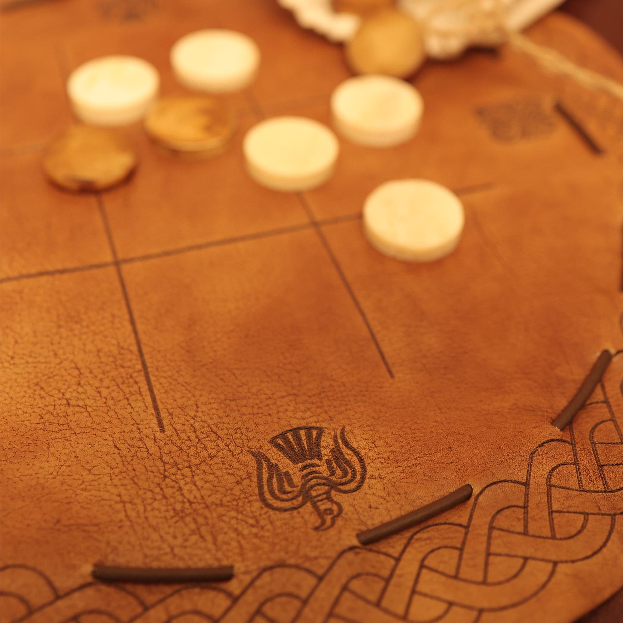 A close-up of the Viking Leather Tic Tac Toe Game, featuring white and brown round pieces on a leather board with Celtic knots and a thistle emblem for a beautifully textured, handcrafted Viking look.