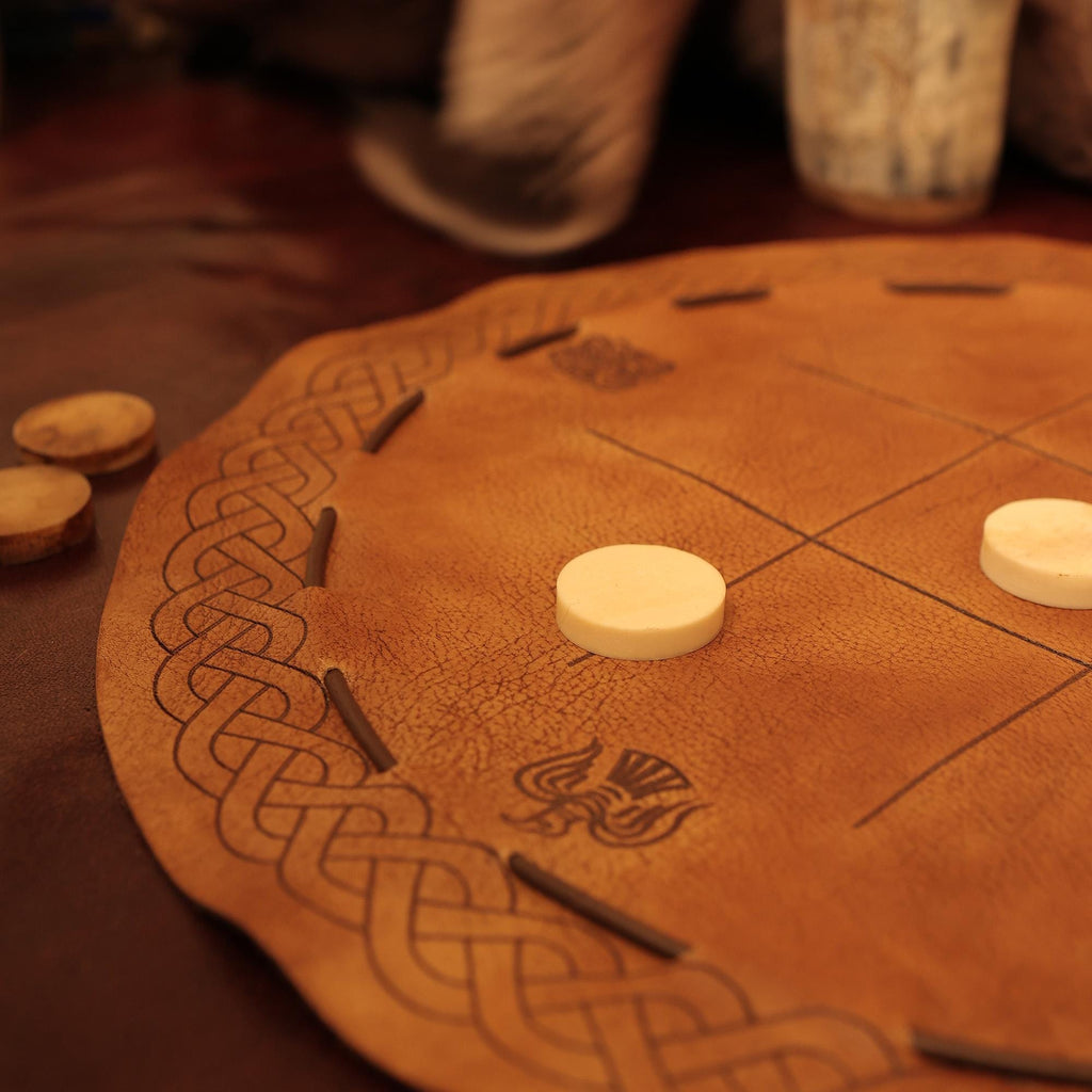 A close-up of the Viking Leather Tic Tac Toe Game shows its handcrafted board with Celtic knot designs, grid lines, and round pieces—evoking the charm of a traditional Viking board game.