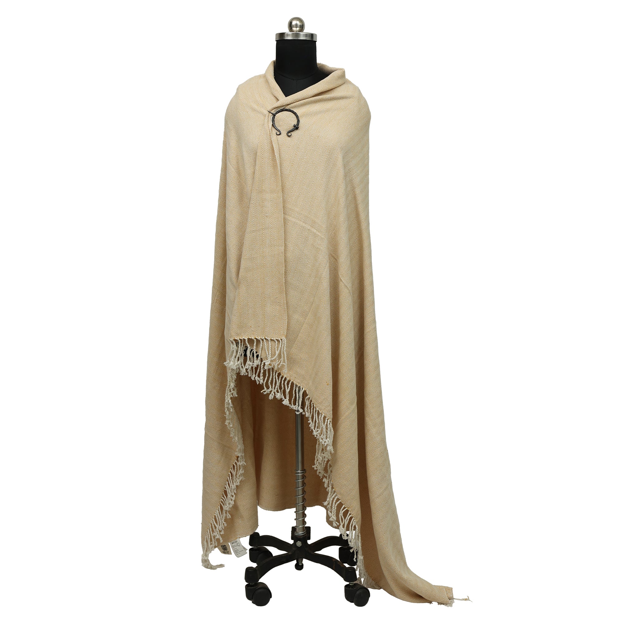 A mannequin showcases Odin's Viking Cape-Unisex, a beige fringed shawl, on a black wheeled stand against a white background.