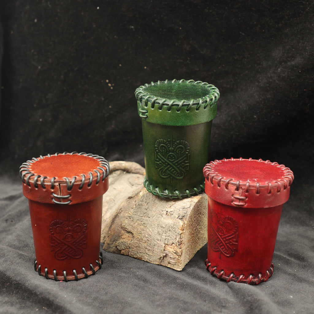 The Handcrafted Dark Red Leather Dice Cup features decorative stitching and embossed designs, making it a perfect tabletop RPG accessory or unique handmade dice cup, styled on wood with a black fabric background.