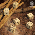 Six handcrafted Bone Dice – Set of 6 Viking Style 6-Sided Dice with circular dot patterns rest on fur, surrounded by wooden sticks, with the Norse Alley logo in the upper right corner.