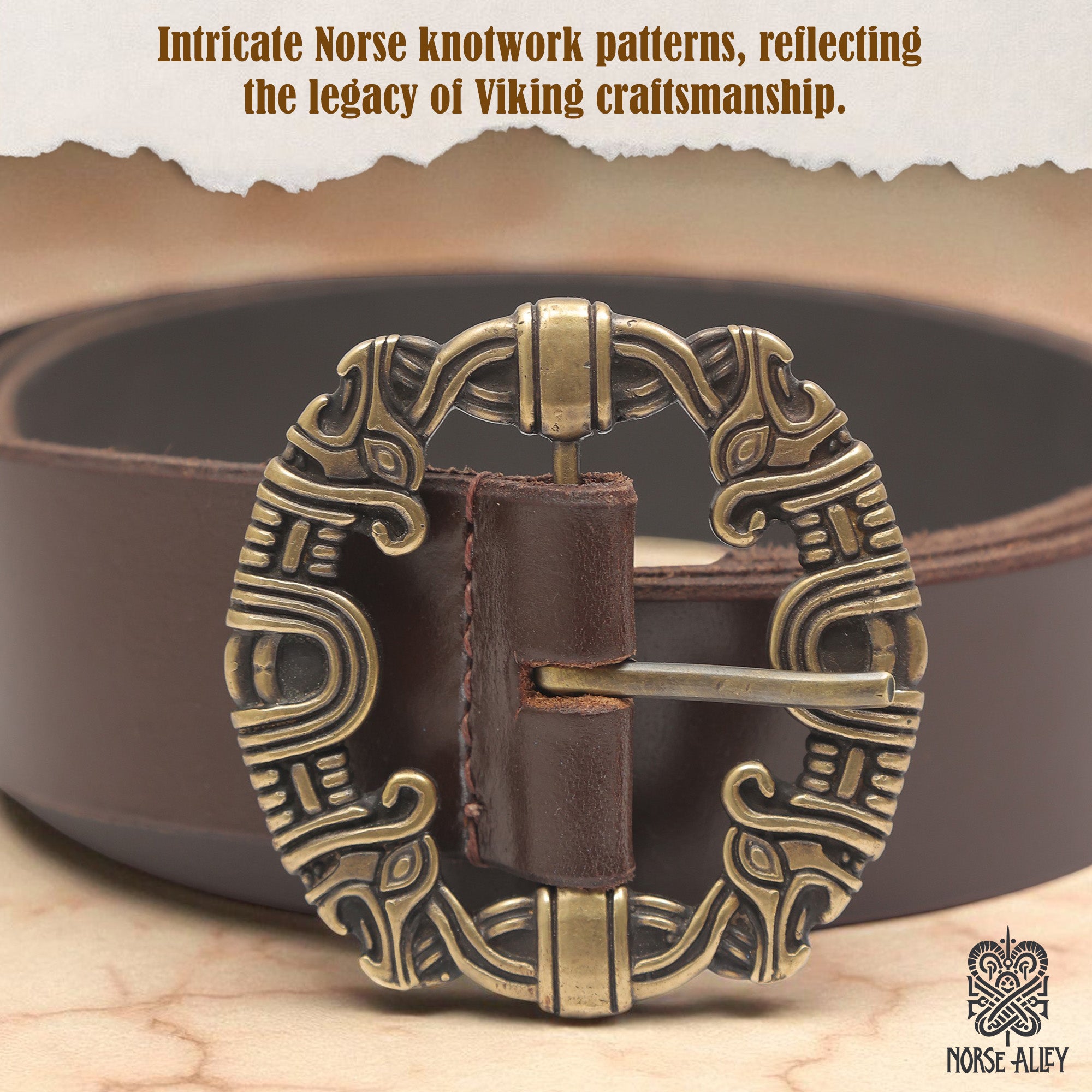 The Norse Alley The Drakkar Belt is a brown Viking leather belt with an ornate antique gold buckle detailed with Norse knotwork. Its design is inspired by Viking artistry, and the Norse Alley logo appears at the bottom right.