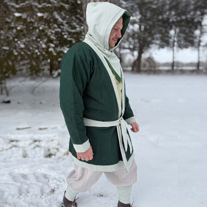 A person wearing a Viking Wool Coat for men, along with beige pants and boots, walks outside in a snowy, wooded landscape.