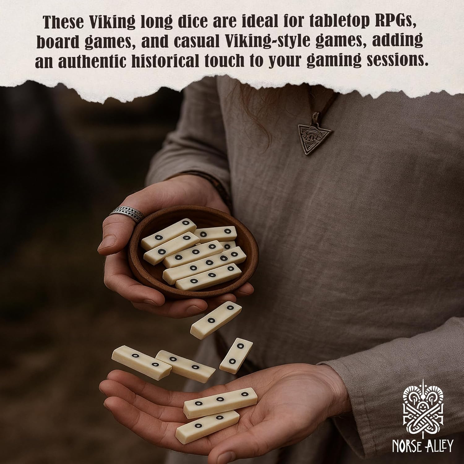 A person in a tunic holds a Viking Bone Dice Set of 5—handcrafted dice inspired by Viking gaming—in one hand and a bowl of medieval accessories in the other. Perfect for tabletop RPGs and board games. Norse Alley logo at bottom right.
