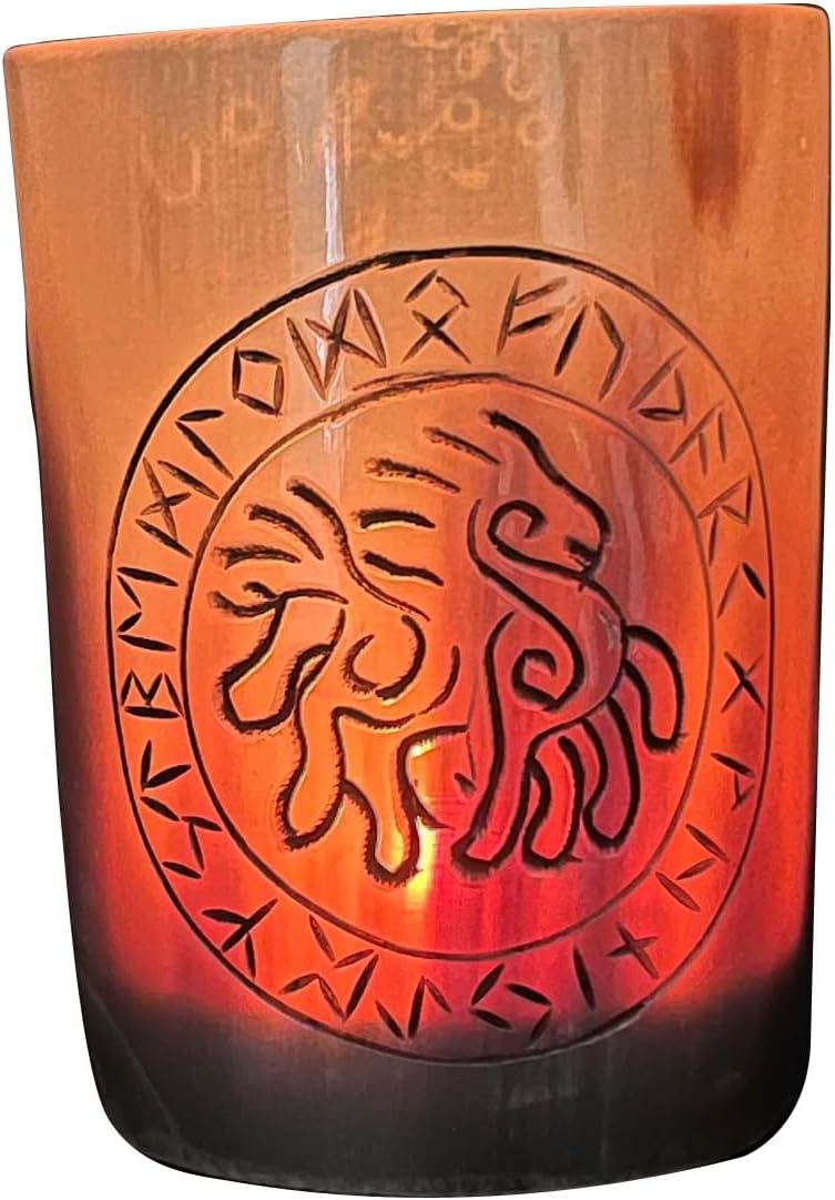 The Norse Alley Viking Drinking Horn Shot Glass is orange and translucent, with a black etched lion inside a circle ringed by ancient-style runes. Its candle casts a warm, glowing effect, echoing the look of horn handicrafts.
