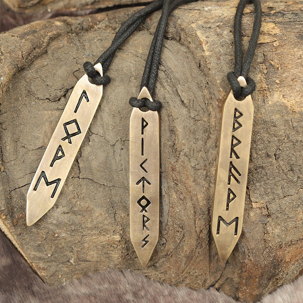 The Norse Alley Viking Runes Brass Pendant Necklace Set (Set of 3) features blade-shaped pendants on black cords, each engraved with Viking runes—a striking choice for those who love unique Nordic brass jewelry.