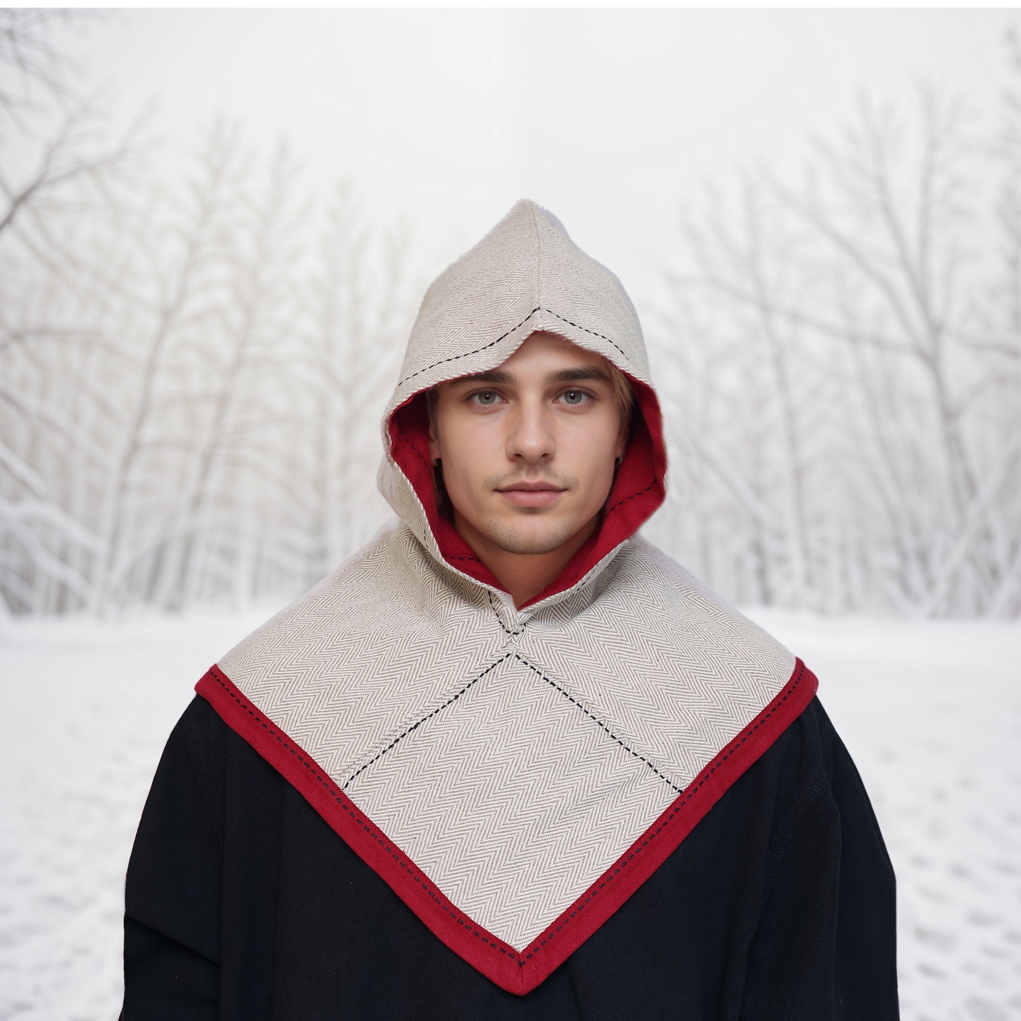 Outdoors in a snowy landscape, a person wears the Reversible Viking Hood, Skjoldehamn and a black coat, channeling medieval vibes amid bare winter trees.