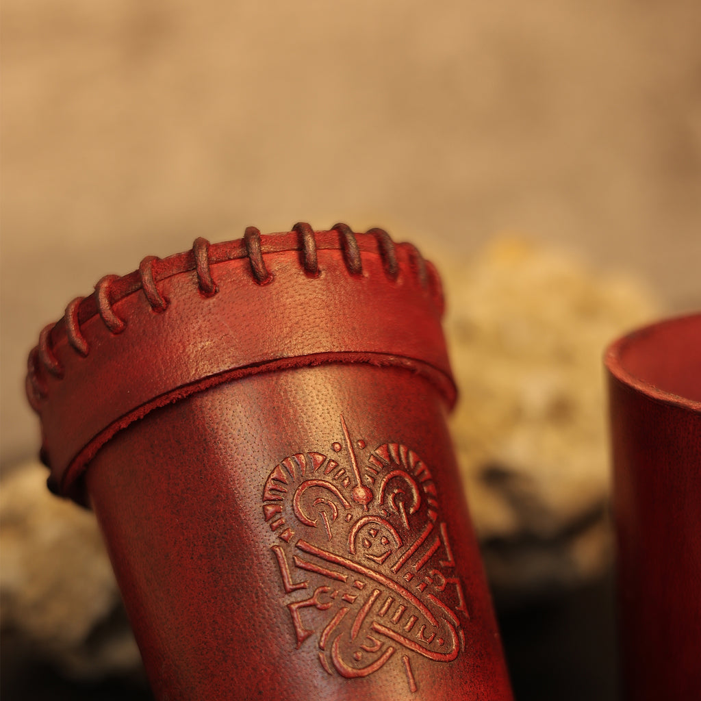 Close-up of the Handcrafted Dark Red Leather Dice Cup, featuring decorative rim stitching and an embossed intricate side design, set against a blurred beige background—ideal for tabletop RPG accessories.