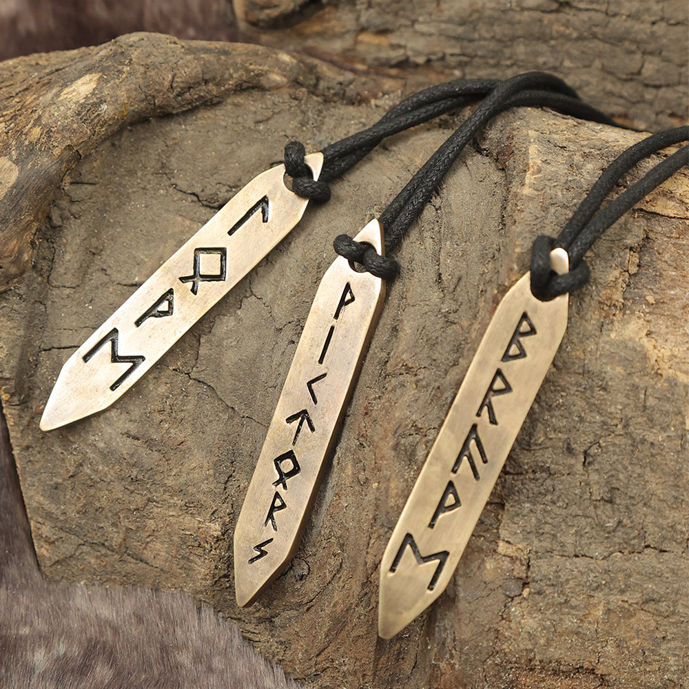 The Norse Alley Viking Runes Brass Pendant Necklace Set (Set of 3) features three pointed metal pendants on black cords, each engraved with unique Viking runes and displayed on wood for striking, symbolic jewelry.