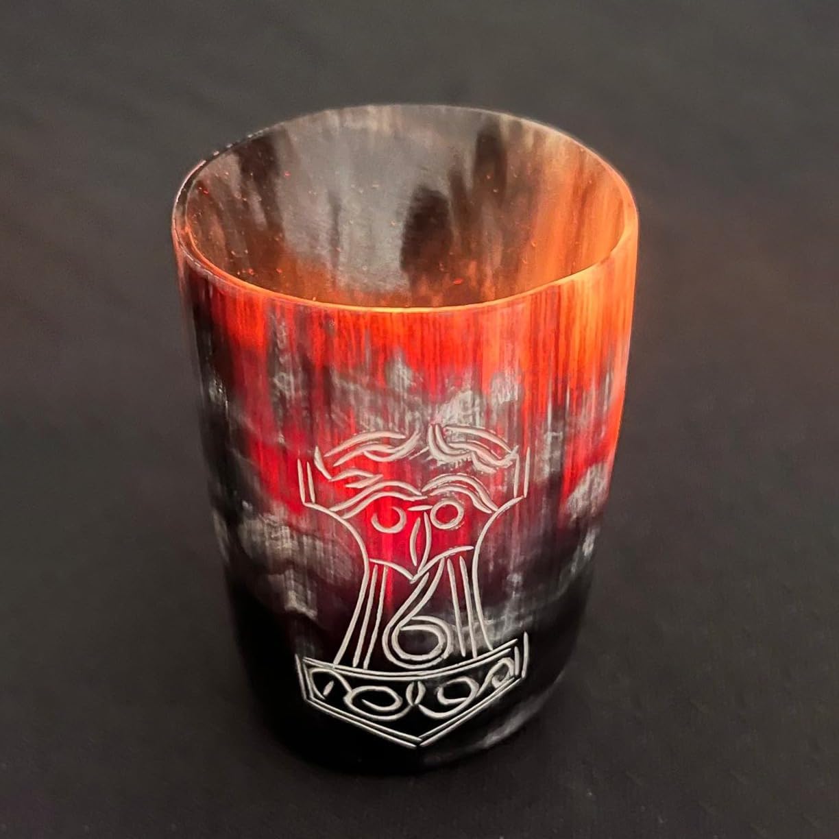 The Norse Alley Viking Drinking Horn Shot Glass features black, red, and orange streaks with an engraved Norse symbol—ideal as unique home decor or a standout piece in your drinking cup collection. Set against a dark background.