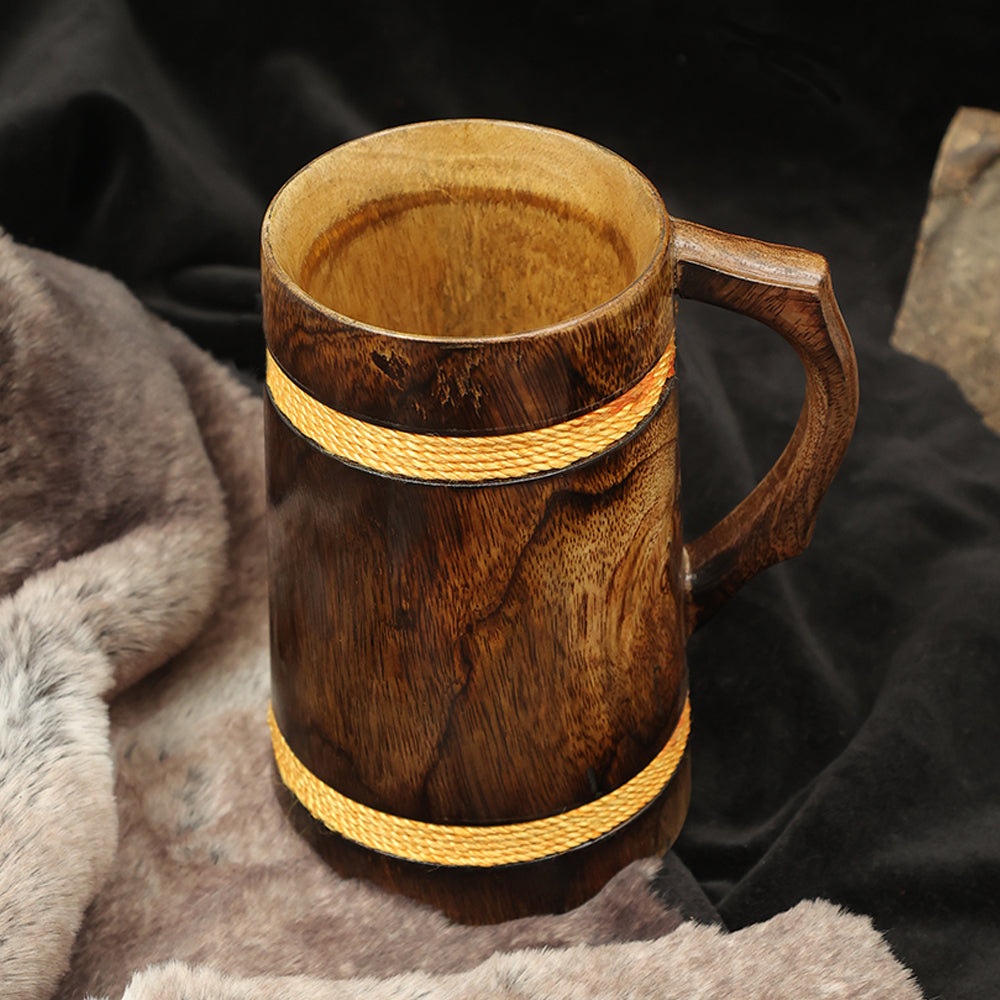 The Wooden Beer Mug with Antique Golden Thread has a sturdy handle and features two light-colored bands, resting on a brown and gray fur surface against a dark background—ideal for authentic Norse décor.