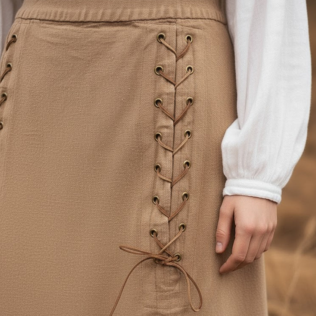 A close-up of a person wearing the Medieval Skirt- Ladies in tan with brown laces through metal eyelets, paired with a long-sleeved white blouse—ideal for Renaissance fair costumes.