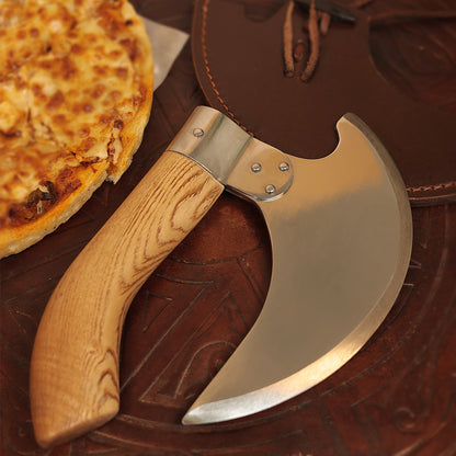 A close-up of the Pizza Axe with Brown Scabbard, a uniquely shaped pizza cutter featuring a lightweight wooden handle and a curved stainless steel blade, placed next to a pizza on a brown leather surface.