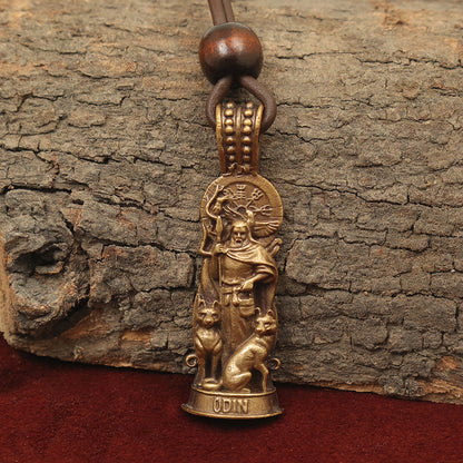 The Odin Pendant – The Allfather is a bronze brass pendant showing Odin with a spear, two wolves, and Norse symbols above. It hangs from a leather cord with a wooden bead, presented on rough tree bark.