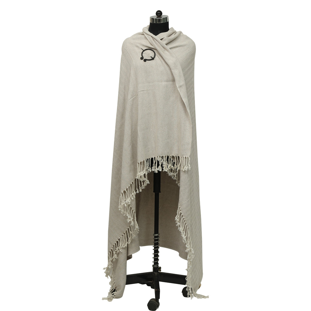 Odin's Viking Cape - Unisex in beige with fringe is draped over a black dress form, featuring a small black headset icon embroidered on the upper left side.
