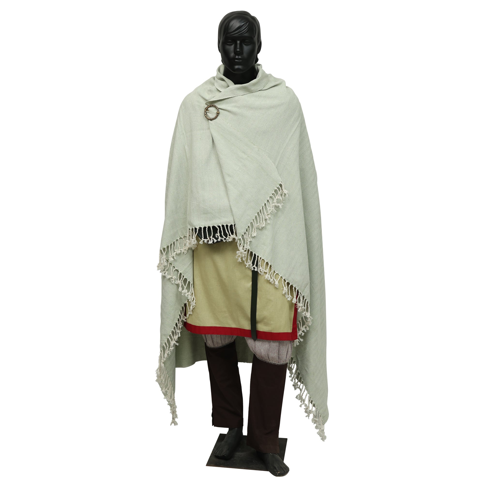 A black mannequin displays Odin's Viking Cape—Unisex: a pale, fringed cloak fastened by a brooch over layered tunics with red hem, loose trousers, and dark boots. The Norse-inspired ensemble stands atop a black base.